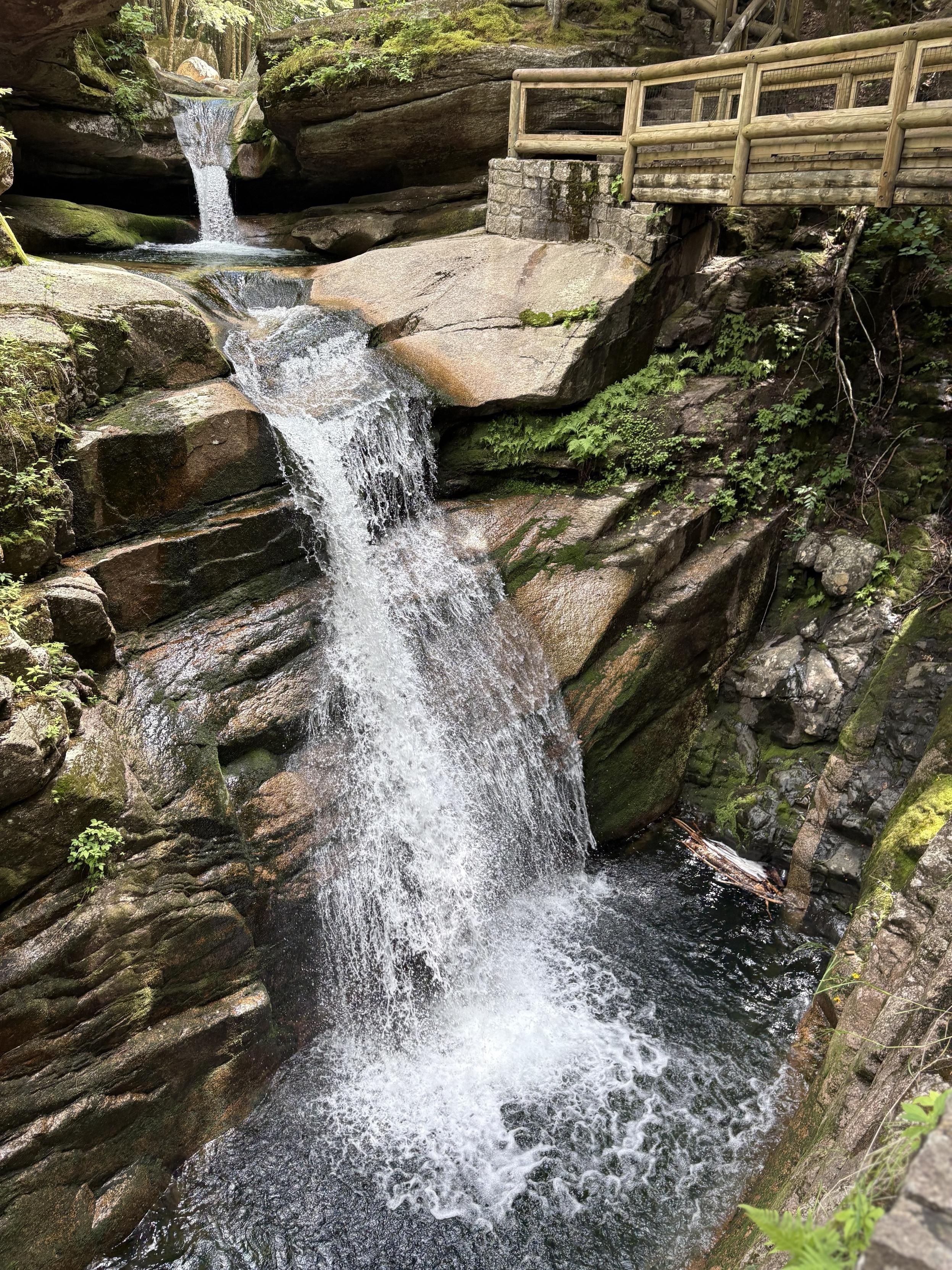View from above the waterfall seen in the first picture. Water is cascading down a granite face into a clear into the linear gash formed by erosion of the basalt dike, which can be seen clearly in its uneroded form, with a granite stringer, on the back wall on the right of the picture.
